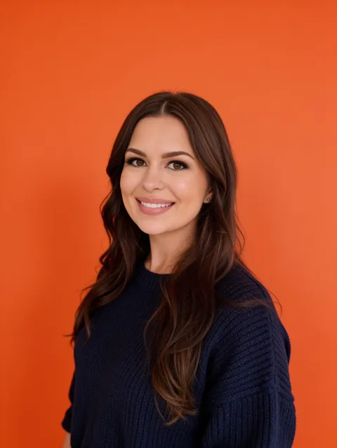 Shayne smiling in a navy sweater against an orange background